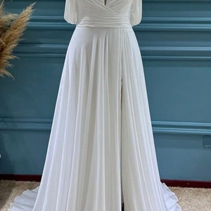 May include: A white off-the-shoulder maxi dress with a sweetheart neckline, a fitted bodice, and a flowing skirt with a thigh-high slit.