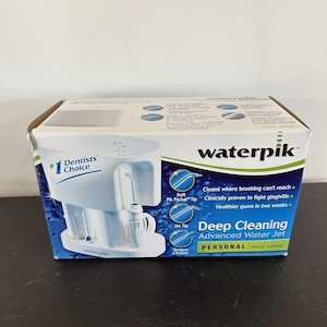 May include: A white Waterpik Deep Cleaning Advanced Water Jet personal dental system box. The packaging features blue and green accents, text including #1 Dentists' Choice, and illustrations of the device with various tips like the Jet Tip.