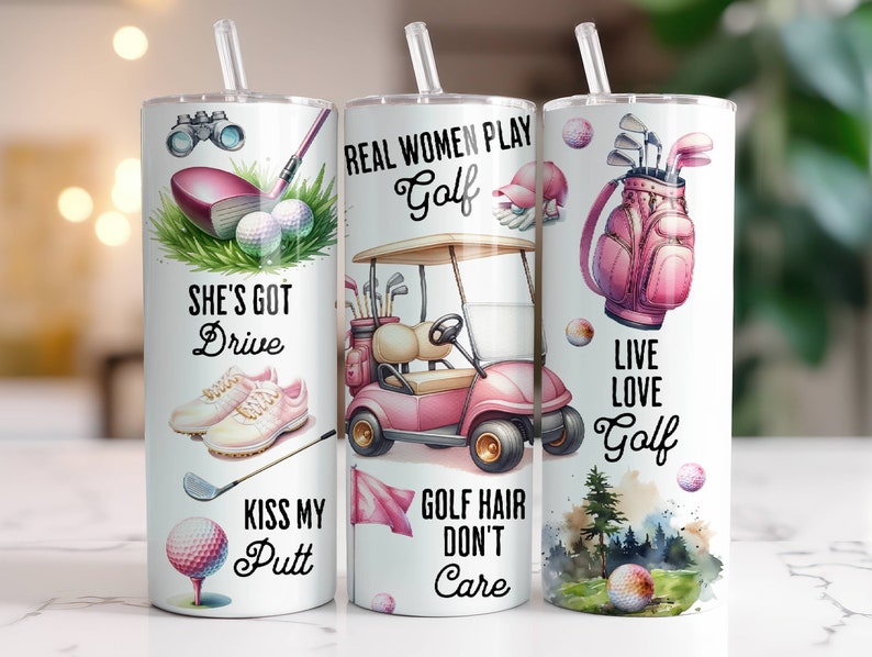 May include: Three white tumblers with pink and green designs. The tumblers feature golf-themed illustrations and text, including "She's Got Drive", "Real Women Play Golf", and "Live Love Golf".