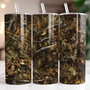 May include: Three stainless steel tumblers with lids and straws. The tumblers are covered in a camouflage pattern with brown, green, and tan colors.