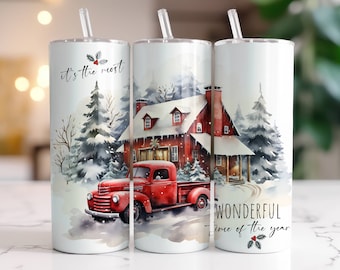 Op de afbeelding: Een witte tumbler met een winterscène met een rode vrachtwagen, een rood huis en met sneeuw bedekte bomen. De tekst "it's the most wonderful time of the year" staat op de tumbler.