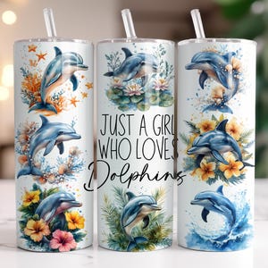 May include: White stainless steel tumbler with a dolphin theme. The tumbler features illustrations of dolphins, flowers, and the text "Just a Girl Who Loves Dolphins." Includes a clear straw.