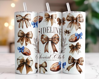 Può includere: Un bicchiere bianco con un design ad acquerello marrone e blu con palloni da calcio e fiocchi. Il bicchiere ha la scritta "Sideline Social Club - Loud and Proud" stampata su di esso.