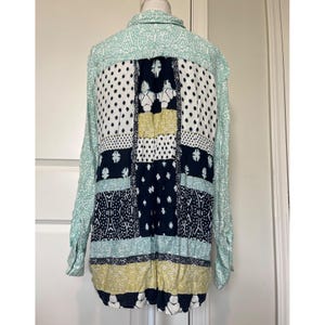 May include: A long-sleeved button-down shirt featuring a patchwork design with various patterns in shades of mint green, navy blue, white, and mustard yellow. The garment displays a mix of geometric, floral, and dotted prints across the back panel.