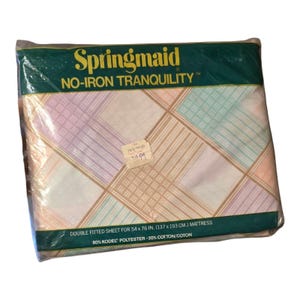 Könnte beinhalten: Eine Verpackung für ein Springmaid No-Iron Tranquility Doppel-Spannbettlaken für eine Matratze von 137 x 193 cm. Das Laken besteht aus 80% Kodel-Polyester und 20% Baumwolle. Das Laken hat ein pastellfarbenes Karomuster.