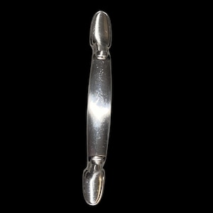 May include: A silver-colored cabinet pull with a curved center and oval ends. The hardware is made of metal and has a shiny finish. The pull is designed for use on drawers or cabinet doors.