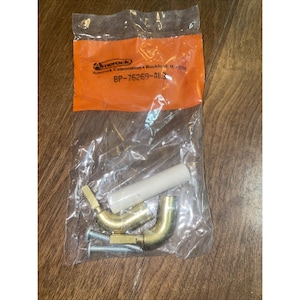 Puede incluir: Una bolsa de plástico transparente que contiene componentes de hardware. La bolsa tiene un encabezado naranja con el texto "Amerock" y "BP-76269-AL3". En el interior hay codos de color latón, una pieza cilíndrica blanca y tornillos plateados.