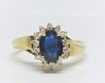 14k Yellow Gold Natural Sapphire Diamond Ring featuring a 7-5 MM natural blue sapphire sourended by a natural white diamond halo.