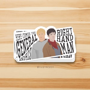 May include: A sticker featuring two cartoon characters, one with blonde hair and a brown sweater, and the other with brown hair and a brown jacket with a red scarf. The text on the sticker reads "Here comes the General and his Right Hand Man".