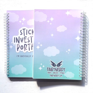 May include: A spiral bound notebook with a light blue and purple gradient background. The notebook has a sticker on the front that says "Stick to your investment portfolio, I'm basically a fairy godmother". The back of the notebook has a logo for Fairy Nerdy, which says "Nerdy. Sarcastic. Feminist. FairyNerdy.com".