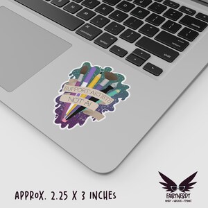 A vinyl sticker with a digital illustration of multiple art tools like paintbrushes, pencils, and markers with a banner that reads, "Support Artists, Not AI." The entire design is on a paint-like green and purple background. Shown on a MacBook.