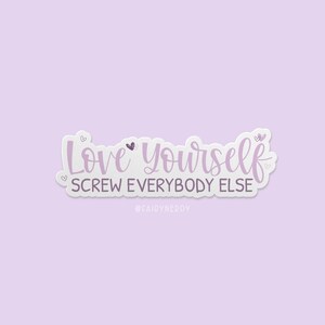 A stack of vinyl die cut sticker with purple text reading, "Love Yourself. Screw Everybody Else."