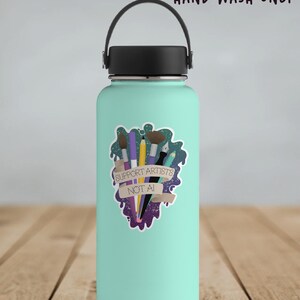 A vinyl sticker with a digital illustration of multiple art tools like paintbrushes, pencils, and markers with a banner that reads, "Support Artists, Not AI." The entire design is on a paint-like green and purple background. Shown on a teal water bottle.