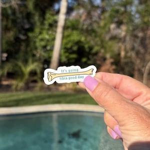 May include: A yellow bone-shaped sticker with the text "It's going tibia good day" in teal lettering.