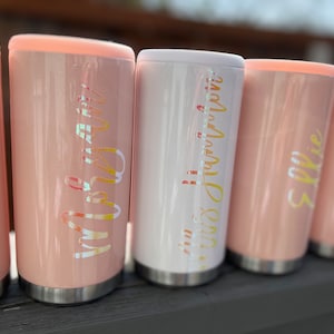 May include: Five pink and white insulated tumblers with gold lettering. The tumblers are lined up in a row. The lettering on the tumblers reads "Jenna", "My Mom", "Mrs. Hawthorne", "Sophie", and "Hannah".