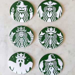 May include: Six green and white round coasters with different Halloween-themed designs. The designs include a witch, a ghost, a skeleton, a mummy, and a pumpkin.