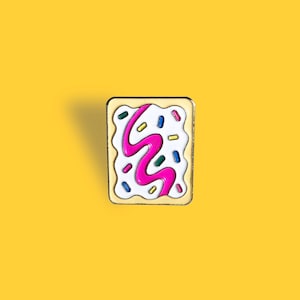 Peut inclure: Épingle carrée en émail représentant une pâtisserie glacée. L'épingle a une base blanche avec un motif rose en forme de vague, des vermicelles colorés et une bordure dorée. L'épingle est posée sur un fond jaune.