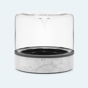 May include: A white marble and glass countertop food storage container with a gray silicone seal. The container has the word "bioasis" printed on the seal.