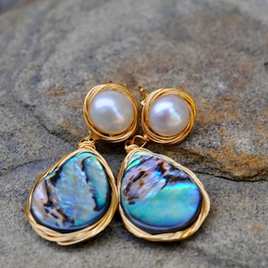 Orecchini pendenti con perla bianca e conchiglia di abalone avvolti in filo metallico.