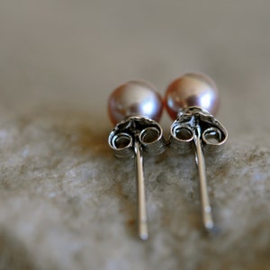 May include: A pair of silver stud earrings with pink pearl accents.