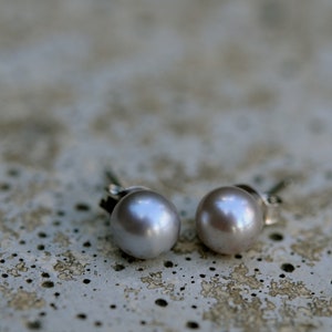 May include: A pair of silver stud earrings with a light gray pearl on each earring.