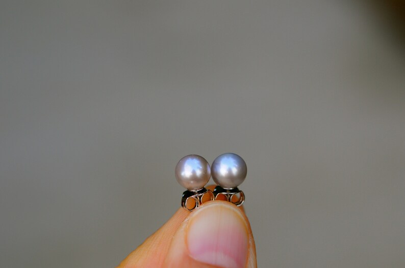 May include: A pair of pearl earrings with silver posts. The pearls are a light gray color.