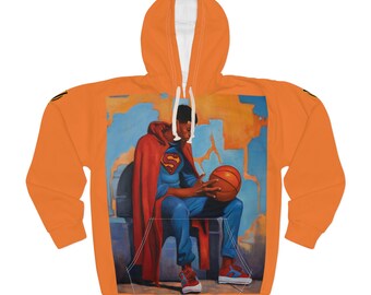 May include: Orange hoodie featuring a Superman-themed graphic. The graphic depicts a person in a Superman costume holding a basketball. The hoodie has a white interior and a drawstring hood. The design is printed on the front.