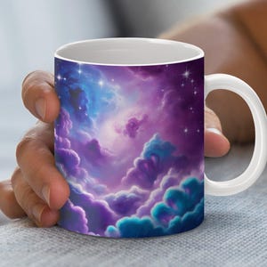 Puede incluir: Taza de cerámica blanca con un diseño de nebulosa colorido en tonos azules, morados y turquesas. La taza tiene un asa y un interior blancos, ideal para bebidas calientes. El diseño presenta estrellas y formaciones nubosas, creando un tema cósmico.