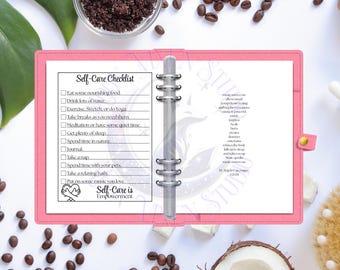 May include: A pink planner with a self-care checklist, including prompts for eating nourishing food, drinking water, and spending time in nature. The planner is open, surrounded by coffee beans, coconut, and other self-care items.