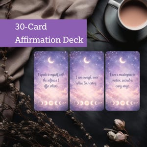 May include: A 30-Card Affirmation Deck with three cards visible, each featuring a crescent moon and celestial design. The cards have affirmations such as "I speak to myself with the softness I offer others." A cup of coffee sits in the background.