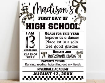 May include: A white sign with black text and decorative bow accents. The sign reads "Madison's First Day of High School." It includes the text "I am 13 years old" and "Goals for this year: Improve as a dancer, place 1st in a solo, get good grades."