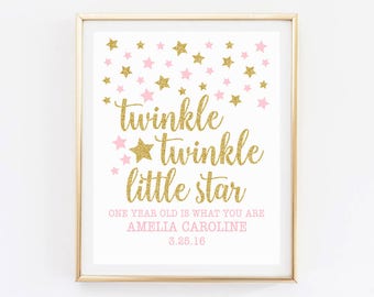 May include: Gold glitter "twinkle twinkle little star" print with pink stars and the text "One year old is what you are Amelia Caroline 3.25.16"