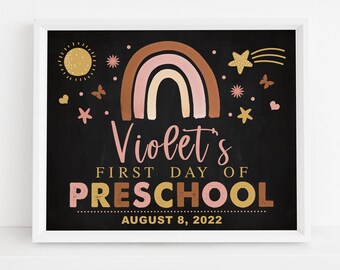 Puede incluir: Un letrero negro de pizarra con un arcoíris, estrellas y mariposas. El texto dice "Violet's First Day of Preschool August 8, 2022".