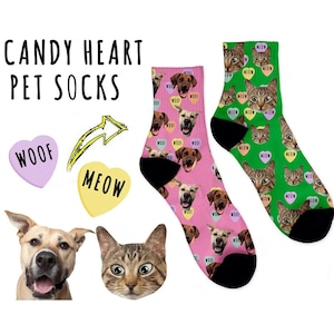 May include: A pair of pink and green socks with a candy heart pattern. The socks feature images of dogs and cats with the words "woof" and "meow" on the hearts.