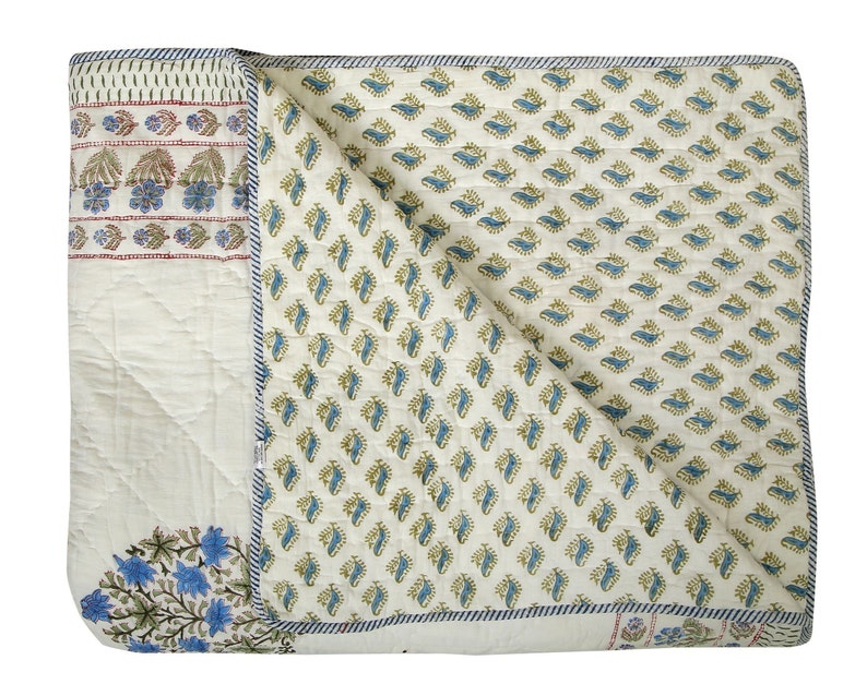 Puede incluir: Una colcha de algod&oacute;n blanco con un patr&oacute;n floral azul y verde. La colcha est&aacute; doblada por la mitad y tiene un fondo blanco con un patr&oacute;n floral azul y verde.