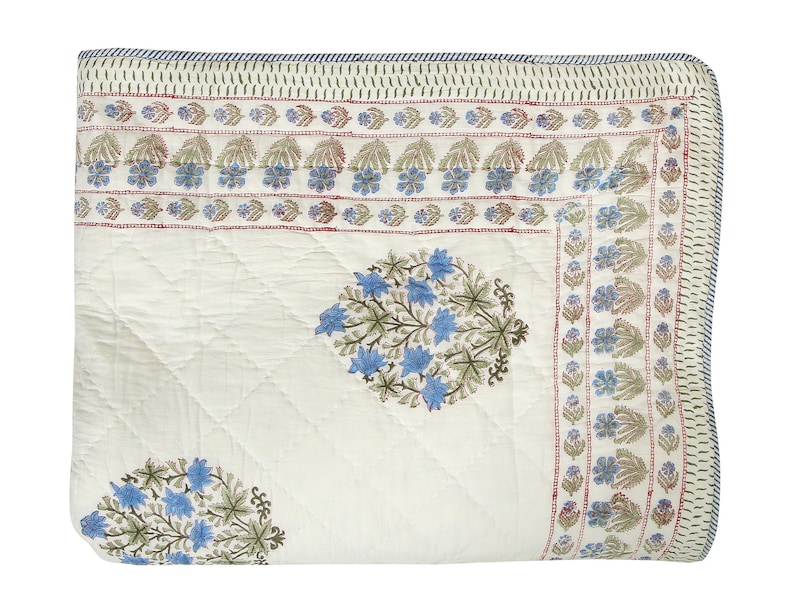 Puede incluir: Una colcha de algod&oacute;n blanco con estampado floral azul y verde. La colcha tiene un borde con un patr&oacute;n floral repetitivo.