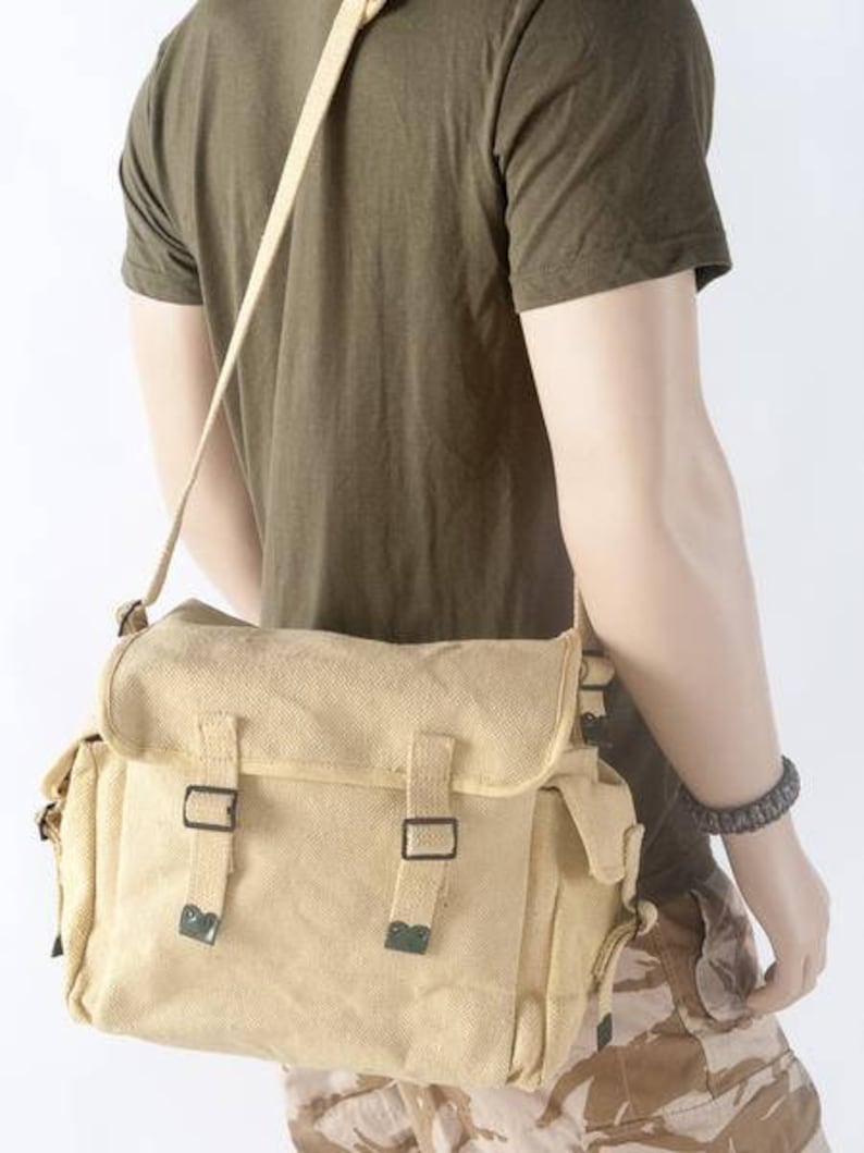 May include: A beige canvas messenger bag with two adjustable straps and a flap closure. The bag has a large main compartment and two smaller pockets on the front.