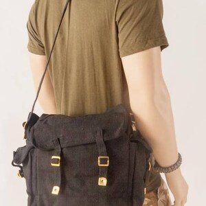 May include: A black canvas messenger bag with gold buckles and a long adjustable strap. The bag has a flap closure and a large main compartment.