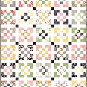 May include: A quilt block pattern with a variety of floral and geometric prints in pink, yellow, green, black, and white. The blocks are arranged in a grid pattern with a black border.