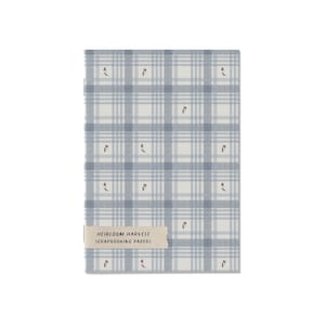 Puede incluir: Un paquete rectangular de papeles para scrapbooking con un patrón de cuadros azul claro y blanco, decorado con pequeñas ilustraciones de tulipanes rojos. Una etiqueta beige en la parte inferior muestra el texto HEIRLOOM HARVEST SCRAPBOOKING PAPERS.