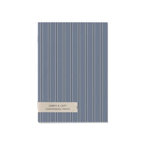May include: A rectangular scrapbook paper pad with a blue and white striped pattern. The words "COMFY & COZY SCRAPBOOKING PAPERS" are printed on a light brown label adhered to the front of the pad. The background is white.