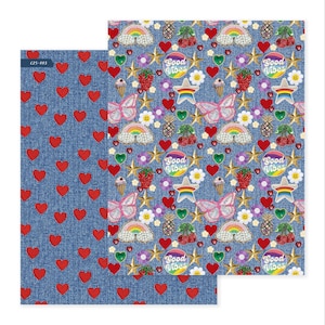 May include: Two sheets of patterned paper. One sheet has a denim-like background with red hearts. The other sheet has a denim-like background with butterflies, rainbows, stars, and the words "Good Vibes".