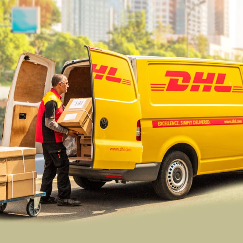 May include: A yellow delivery van with the DHL logo and the words "Excellence, Simply Delivered." A person in a red vest is loading boxes into the back of the van.