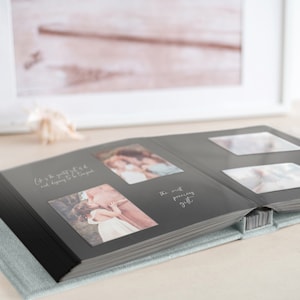 May include: Open photo album with gray pages and several photos. The album is open to a spread with two photos and text that reads "Life is the greatest gift and dispairing to be true good" and "the most precious gift". The album has a light blue cover.