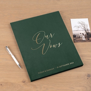 May include: A dark green velvet vow book with gold lettering that reads "Our Vows" and "Susan & Damian - 10 September 2022".
