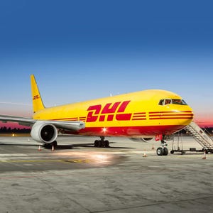 May include: A yellow and red DHL Boeing 767-300F cargo plane on the tarmac at an airport. The plane is parked with its nose facing the camera. The plane has a DHL logo on the side.