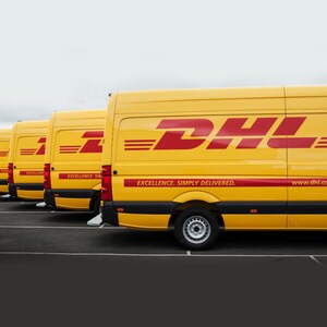 May include: A row of yellow delivery vans with the DHL logo and the slogan "Excellence. Simply Delivered." The vans are parked in a row, with the front of the vans facing the viewer.
