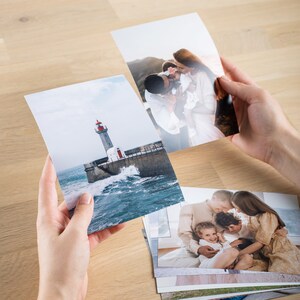 May include: A stack of printed photographs, including a lighthouse on a rocky coast, a family of three, and a couple with a baby.