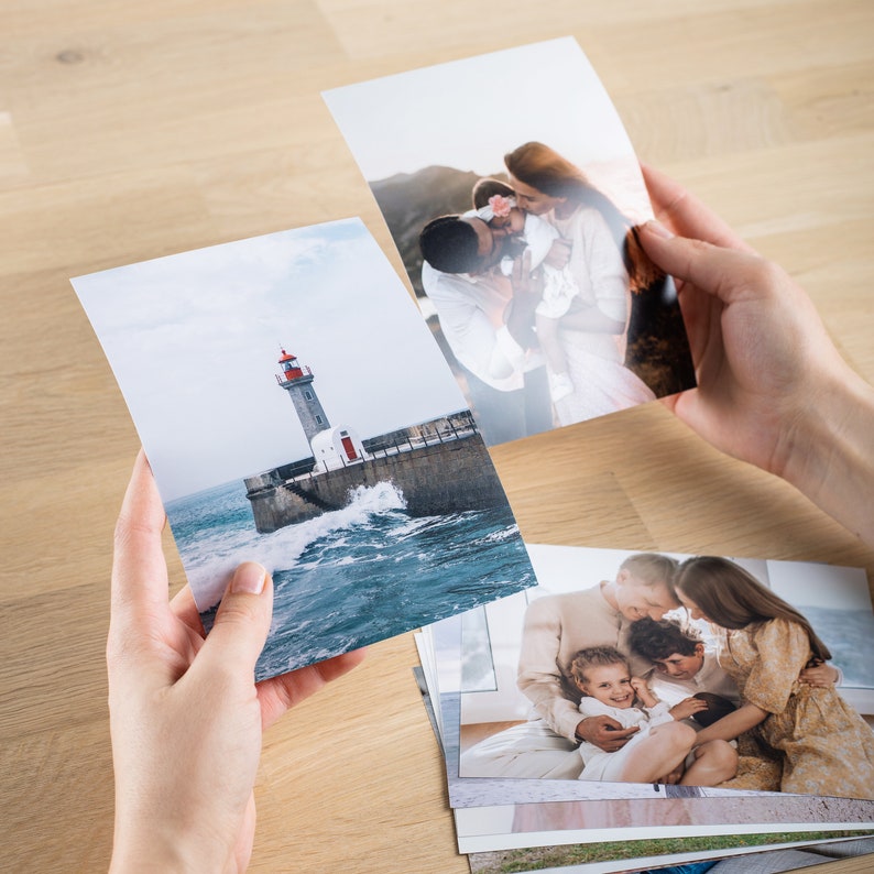 May include: A stack of printed photographs, including a lighthouse on a rocky coast, a family of three, and a couple with a baby.