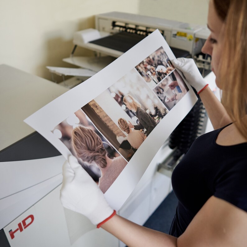 May include: A person is holding a printed photo collage with multiple images of people. The photo is printed on a white background and has a glossy finish.
